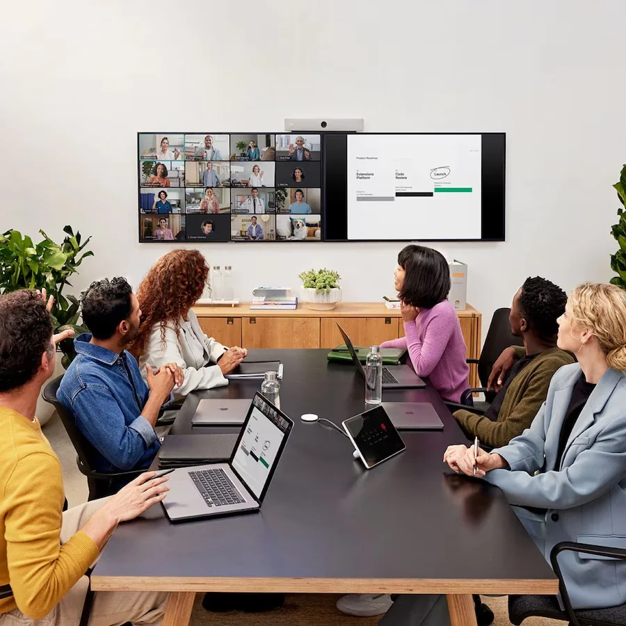 A team collaborating in a meeting room with remote attendees on a video display